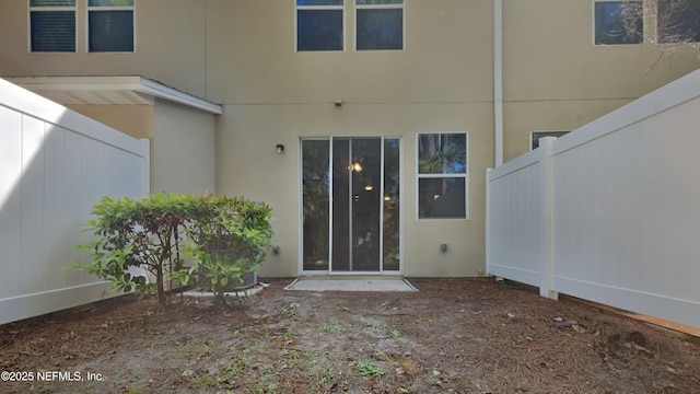 doorway to property featuring fence and stucco siding