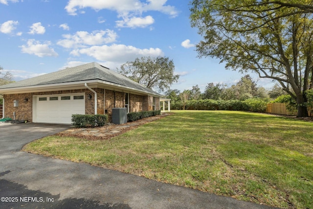 view of side of home with fence, driveway, an attached garage, a yard, and brick siding