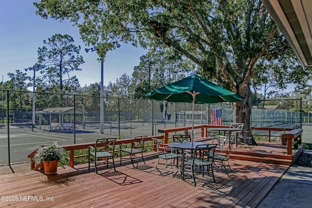 wooden terrace with a tennis court and fence