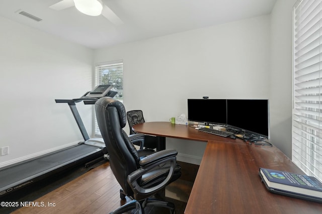 home office with visible vents, baseboards, ceiling fan, and hardwood / wood-style flooring