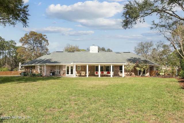 back of house featuring a lawn, french doors, a chimney, and fence