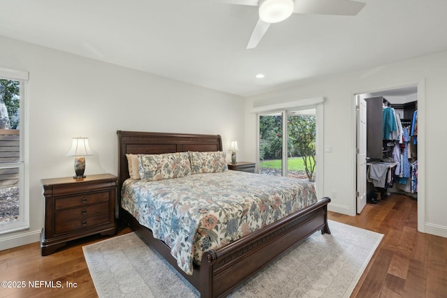 bedroom featuring access to outside, wood finished floors, baseboards, ceiling fan, and a spacious closet