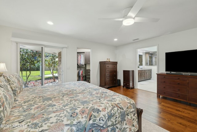 bedroom featuring access to exterior, connected bathroom, a walk in closet, recessed lighting, and wood finished floors