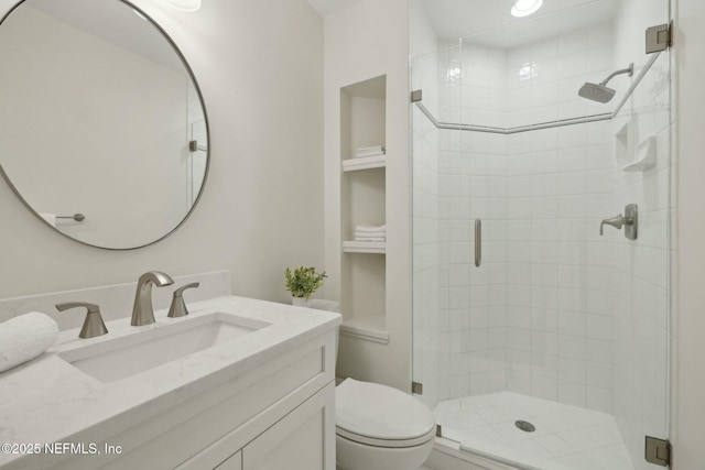 bathroom with built in features, a shower stall, toilet, and vanity