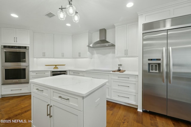 kitchen with visible vents, dark wood finished floors, white cabinetry, stainless steel appliances, and wall chimney exhaust hood