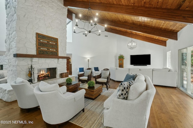 living room featuring beam ceiling, a stone fireplace, wood ceiling, and wood finished floors