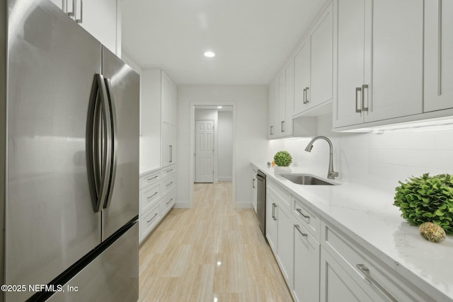 kitchen with white cabinets, backsplash, appliances with stainless steel finishes, and a sink