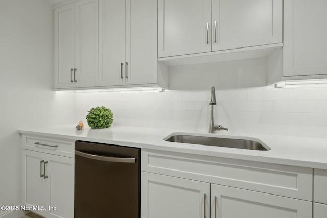 kitchen featuring tasteful backsplash, white cabinetry, stainless steel dishwasher, and a sink