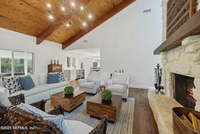 living room featuring baseboards, wood ceiling, a stone fireplace, an inviting chandelier, and wood-type flooring