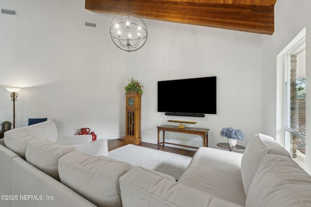 living room with visible vents, beam ceiling, an inviting chandelier, and wood finished floors