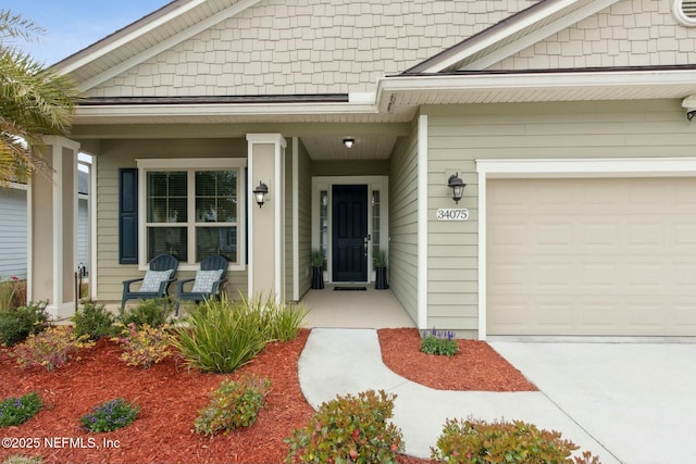 view of exterior entry featuring a porch and an attached garage