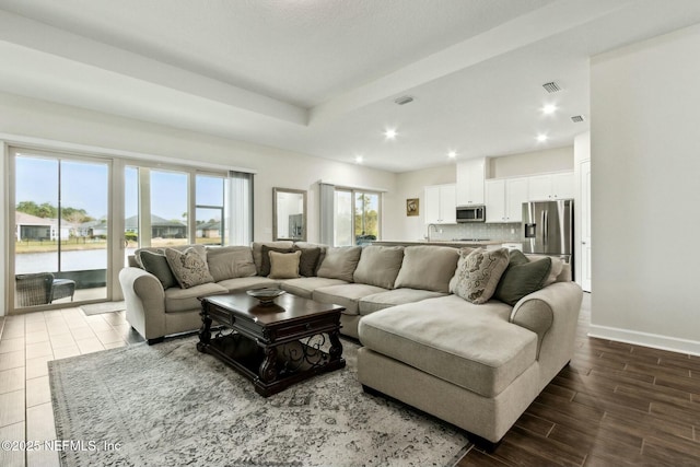 living area featuring recessed lighting, wood finished floors, visible vents, baseboards, and a raised ceiling