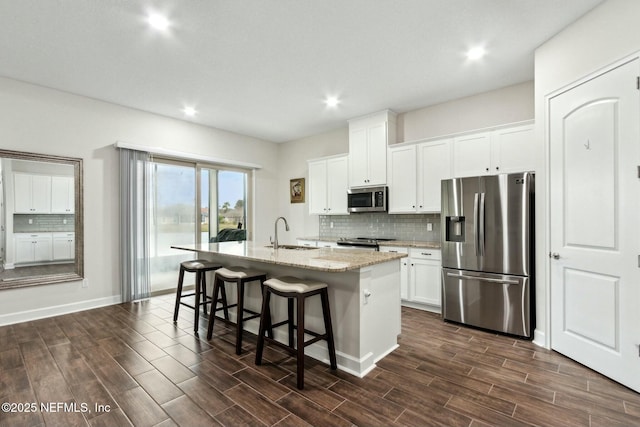 kitchen featuring appliances with stainless steel finishes, wood finish floors, a sink, and a center island with sink