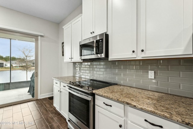 kitchen with stainless steel appliances, backsplash, white cabinets, and light stone countertops