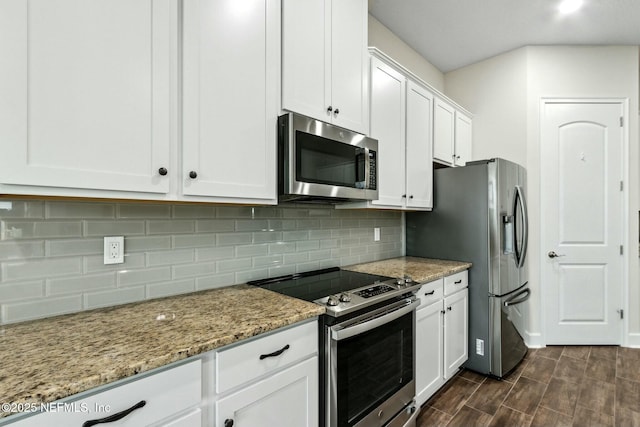 kitchen featuring stainless steel appliances, light stone countertops, white cabinets, and decorative backsplash