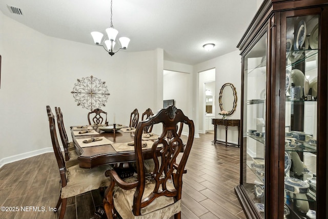 dining space featuring an inviting chandelier, wood tiled floor, visible vents, and baseboards