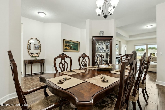 dining room with a notable chandelier, baseboards, and wood tiled floor