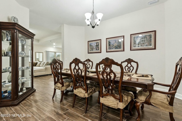 dining area featuring baseboards, wood finish floors, visible vents, and an inviting chandelier