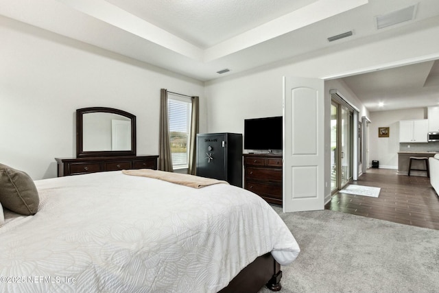 bedroom featuring visible vents, a tray ceiling, and wood finished floors