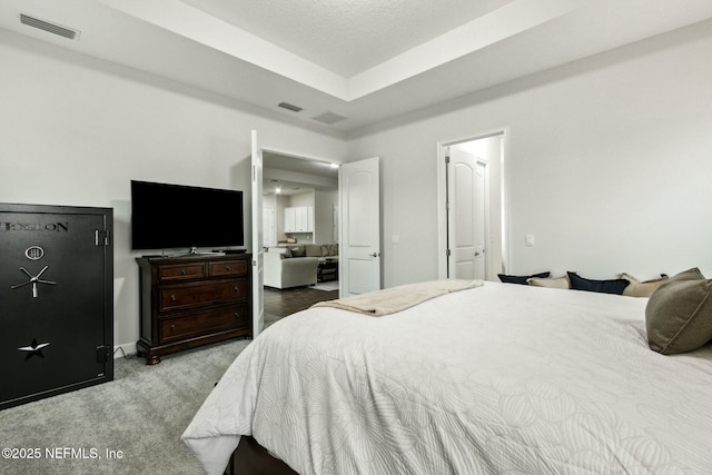 bedroom featuring carpet floors, visible vents, and a raised ceiling