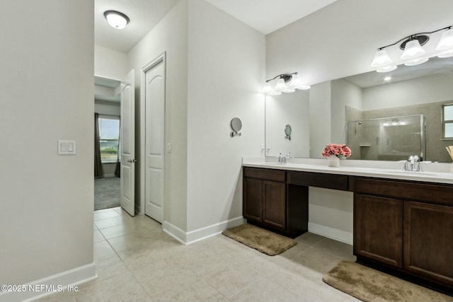 bathroom featuring double vanity, tile patterned flooring, a shower stall, and a sink