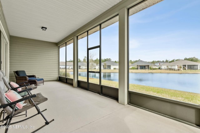 sunroom with a water view, plenty of natural light, and a residential view