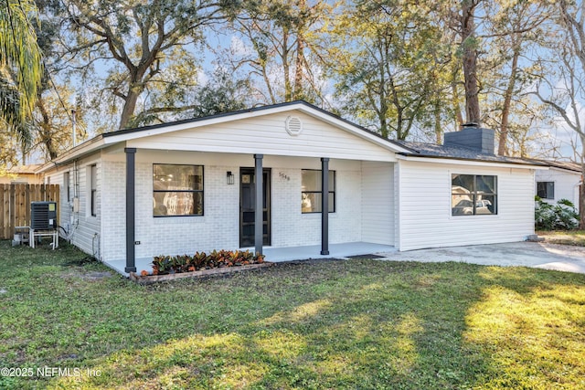 view of front of house featuring brick siding, a chimney, fence, driveway, and a front lawn