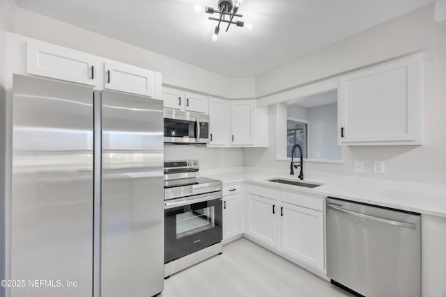 kitchen featuring appliances with stainless steel finishes, white cabinets, and a sink