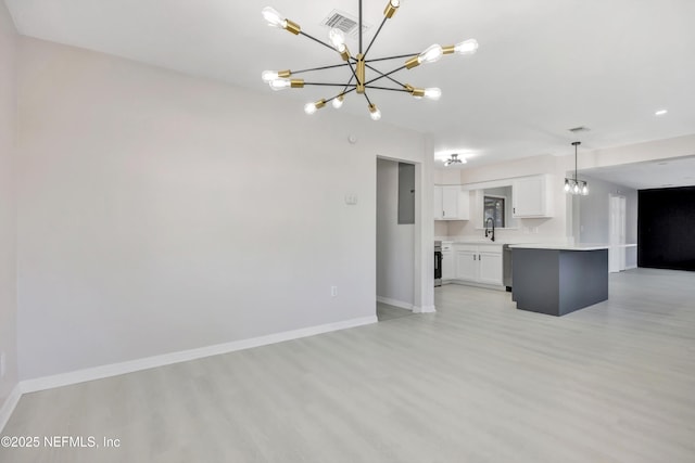 kitchen featuring white cabinetry, baseboards, open floor plan, light countertops, and an inviting chandelier