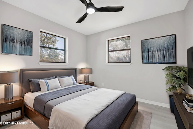 bedroom with multiple windows, ceiling fan, baseboards, and wood finished floors