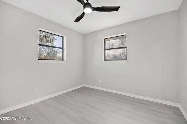 unfurnished room with a healthy amount of sunlight, ceiling fan, baseboards, and wood finished floors