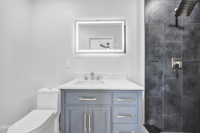 bathroom with tiled shower, vanity, and toilet