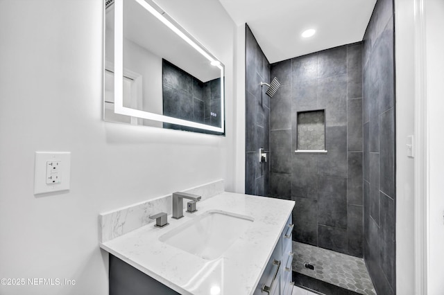 full bath featuring a tile shower and vanity