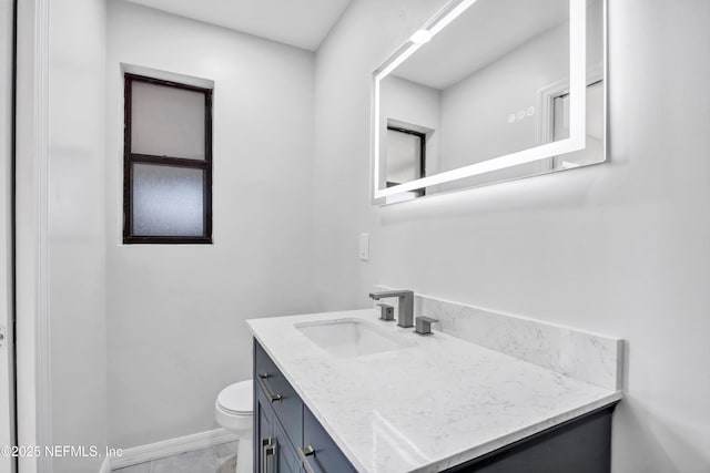 bathroom with toilet, baseboards, and vanity