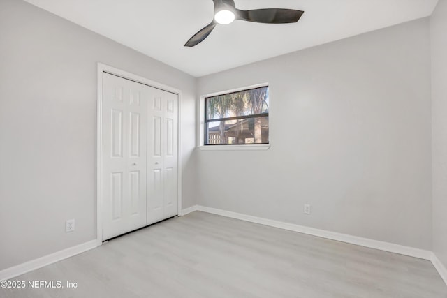 unfurnished bedroom with a ceiling fan, a closet, baseboards, and wood finished floors