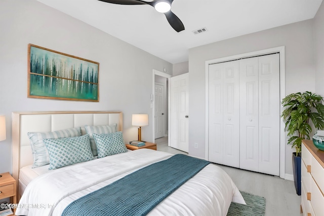 bedroom featuring ceiling fan, a closet, visible vents, and wood finished floors