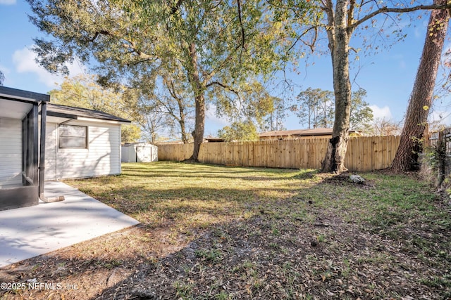 view of yard featuring a patio area, a shed, a fenced backyard, and an outbuilding