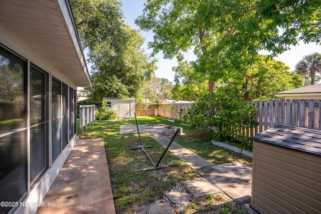 view of yard with a storage shed, a fenced backyard, and an outbuilding