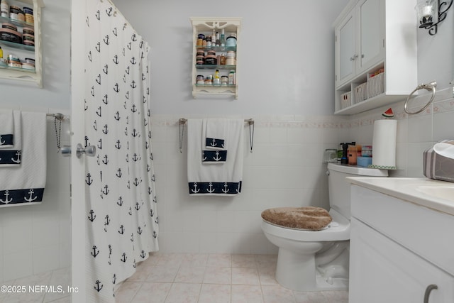 bathroom featuring toilet, tile patterned floors, vanity, tile walls, and a shower with curtain