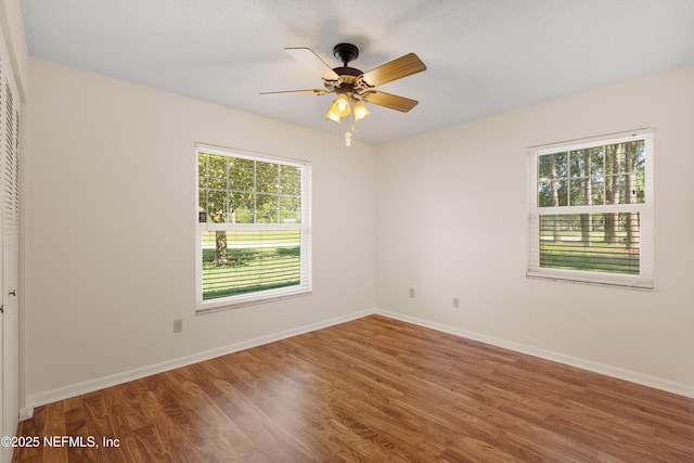 unfurnished room featuring ceiling fan, wood finished floors, and baseboards