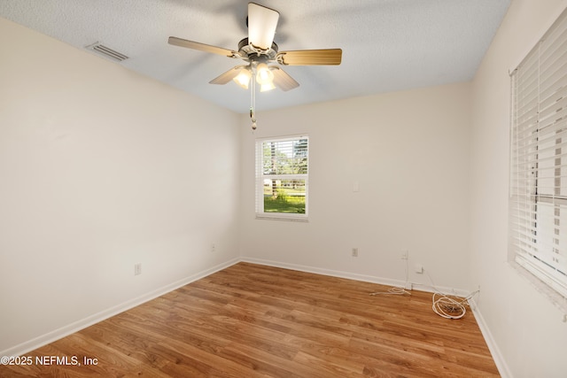 unfurnished room with baseboards, visible vents, a ceiling fan, a textured ceiling, and light wood-style floors