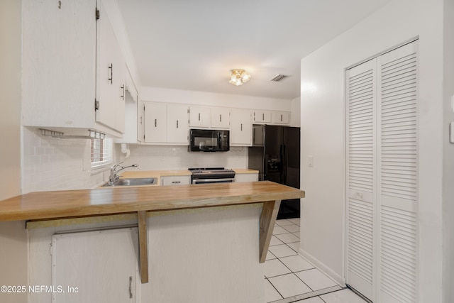 kitchen featuring visible vents, decorative backsplash, a peninsula, black appliances, and a sink