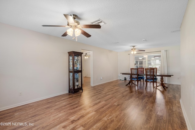 dining room with a textured ceiling, light wood finished floors, visible vents, and baseboards