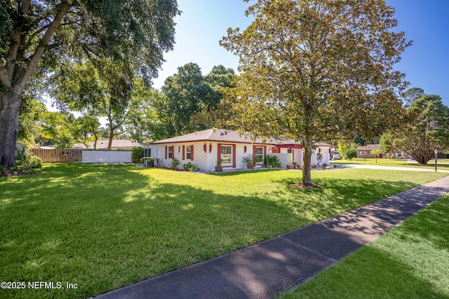 ranch-style home featuring fence and a front lawn