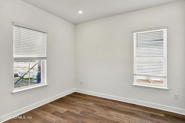 spare room featuring dark wood-style floors, baseboards, and a wealth of natural light