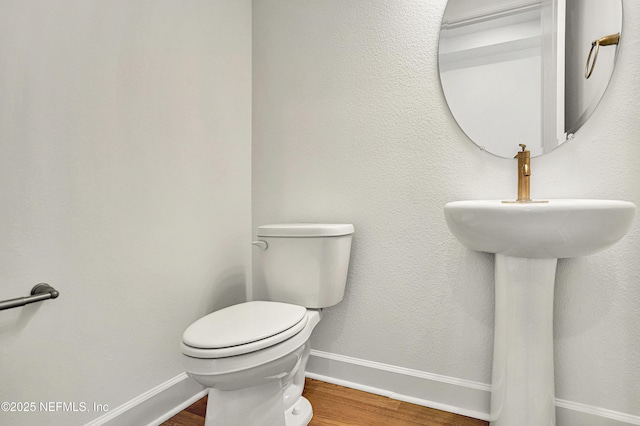 bathroom featuring wood finished floors, toilet, and baseboards