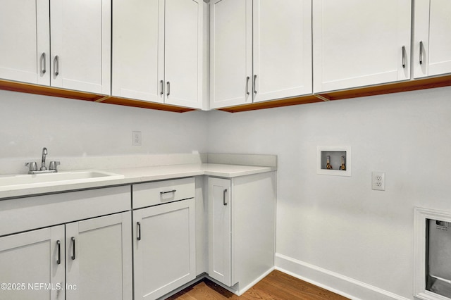 laundry room featuring cabinet space, baseboards, light wood-style flooring, washer hookup, and a sink