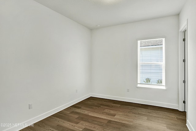 unfurnished room featuring dark wood-style floors and baseboards