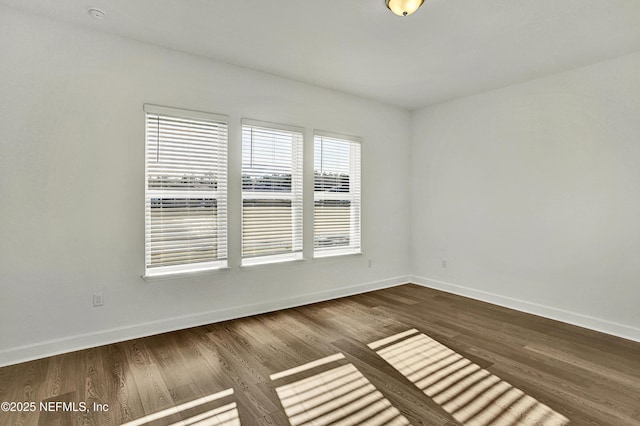 unfurnished room featuring baseboards and dark wood-type flooring