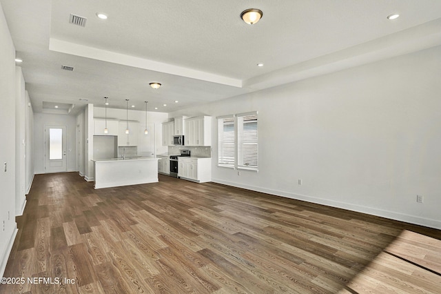 unfurnished living room featuring dark wood-type flooring, recessed lighting, visible vents, and baseboards